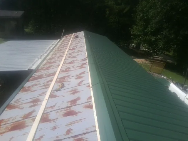 Old rusted panels beside newly installed green metal roofing — Wind Damage Roof Repair by Roofing Brothers in Elwood