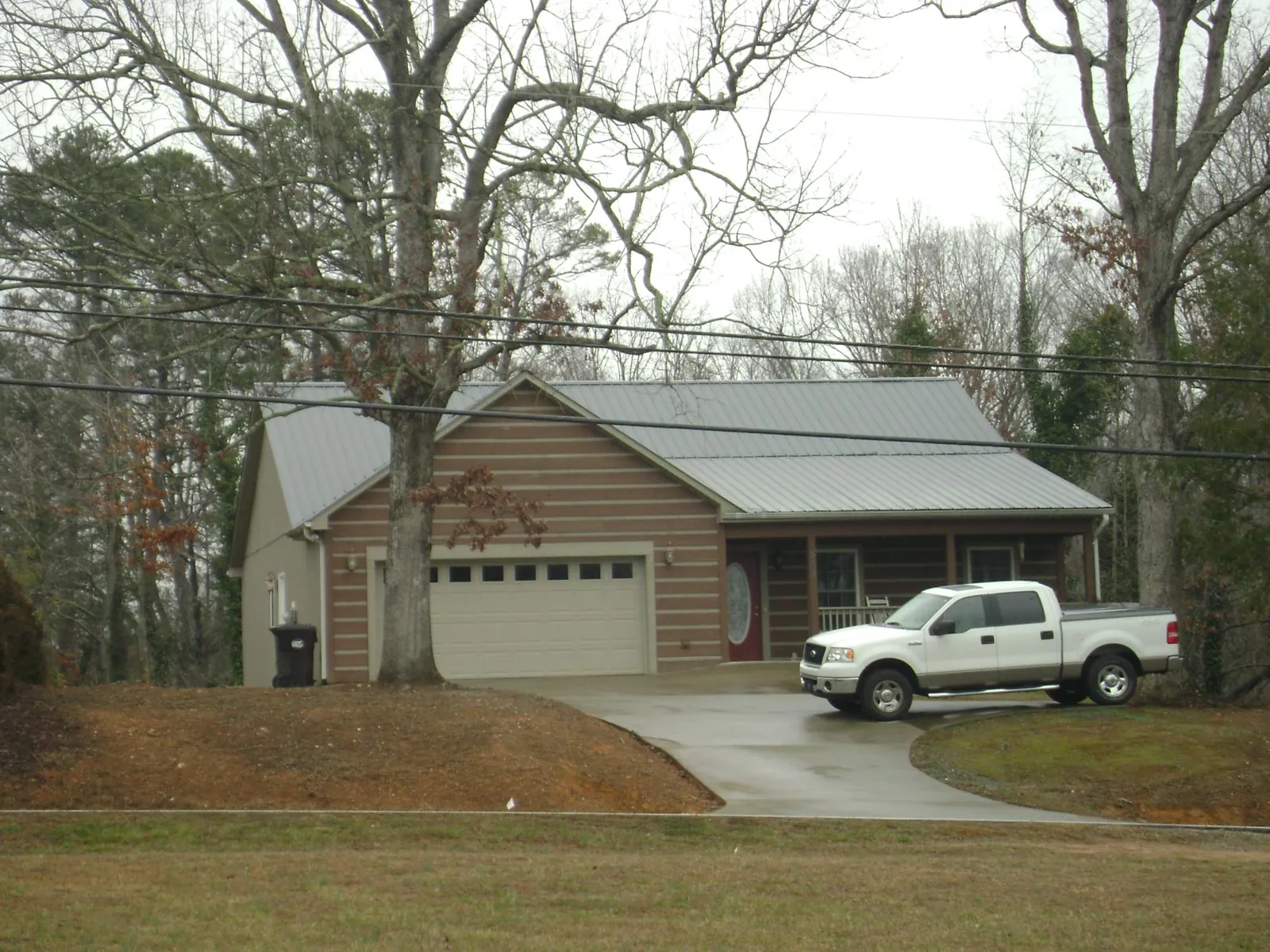 Gray metal roof on a log sided house with an attached two car garage in Elwood